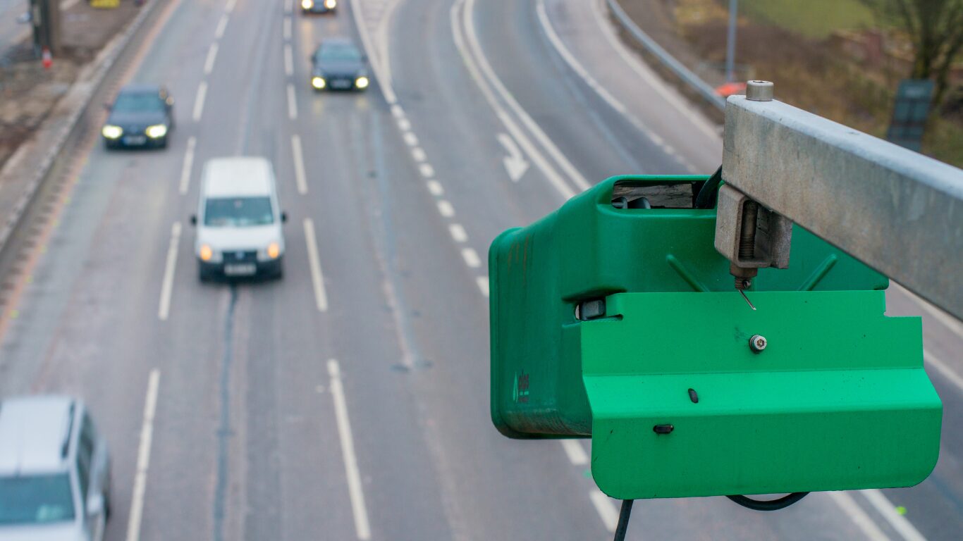 A green ANPR camera on above road monitoring traffic