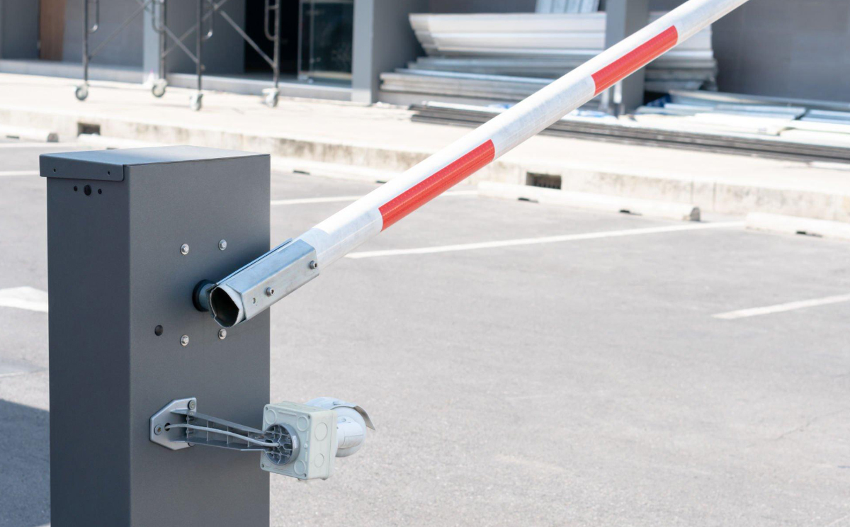 A close-up of an automatic security barrier gate in a raised position at the entrance of a car park.