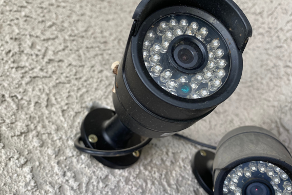 Close-up of two black security cameras mounted on a textured wall
